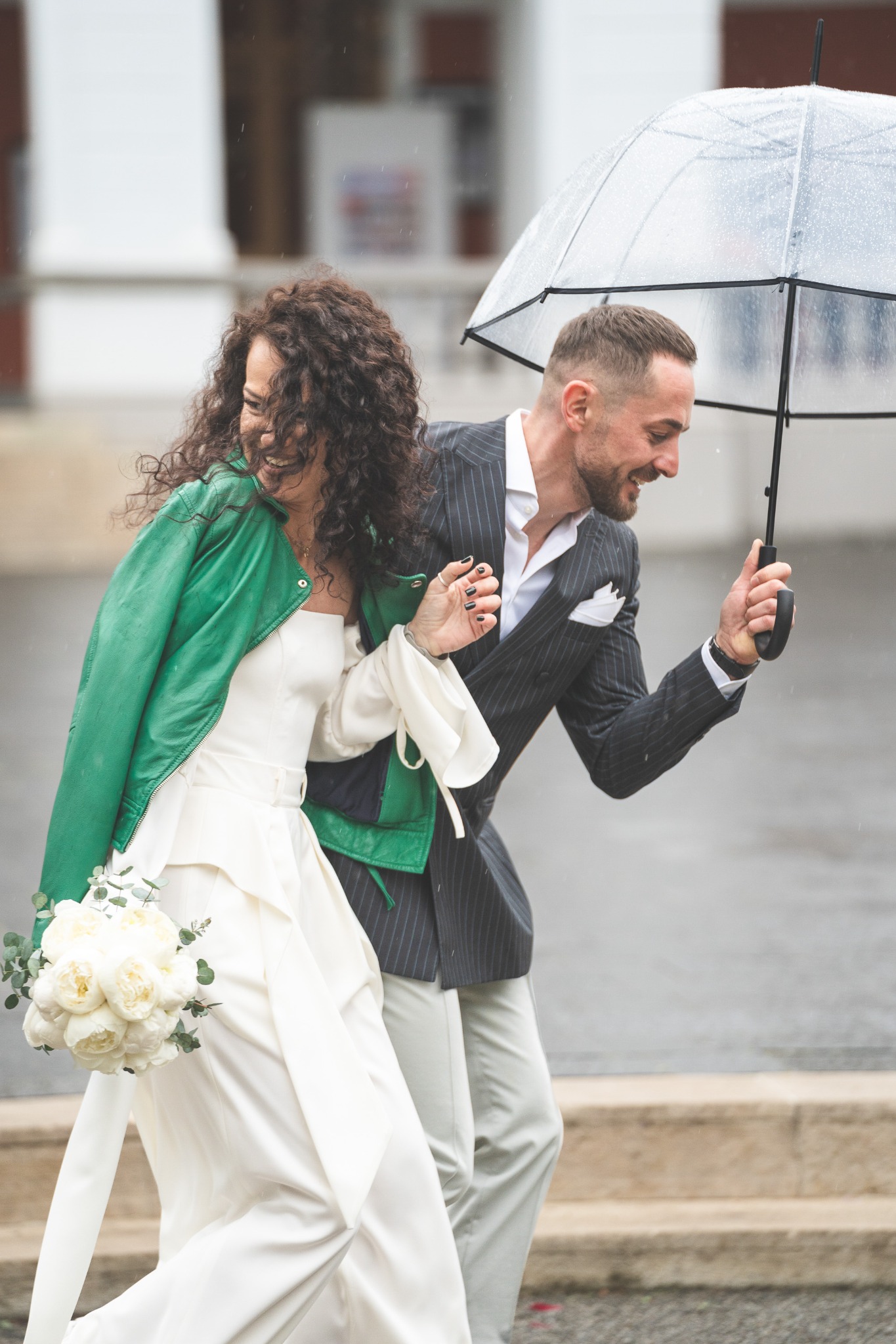 Newlyweds walking under an umbrella in the rain